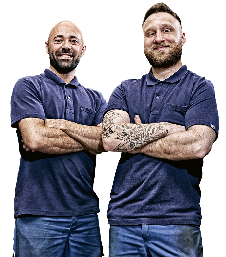 Dos hombres con polos azules y los brazos cruzados.