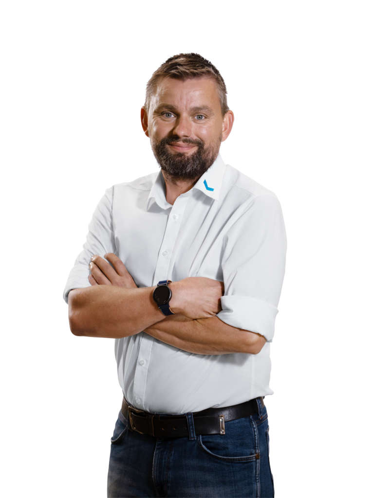 Mann in weißem Hemd und Jeans steht mit verschränkten Armen.