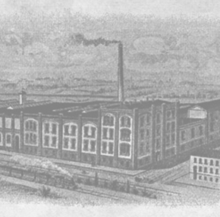 Historische Fabrik mit Schornstein und rauchendem Kamin.