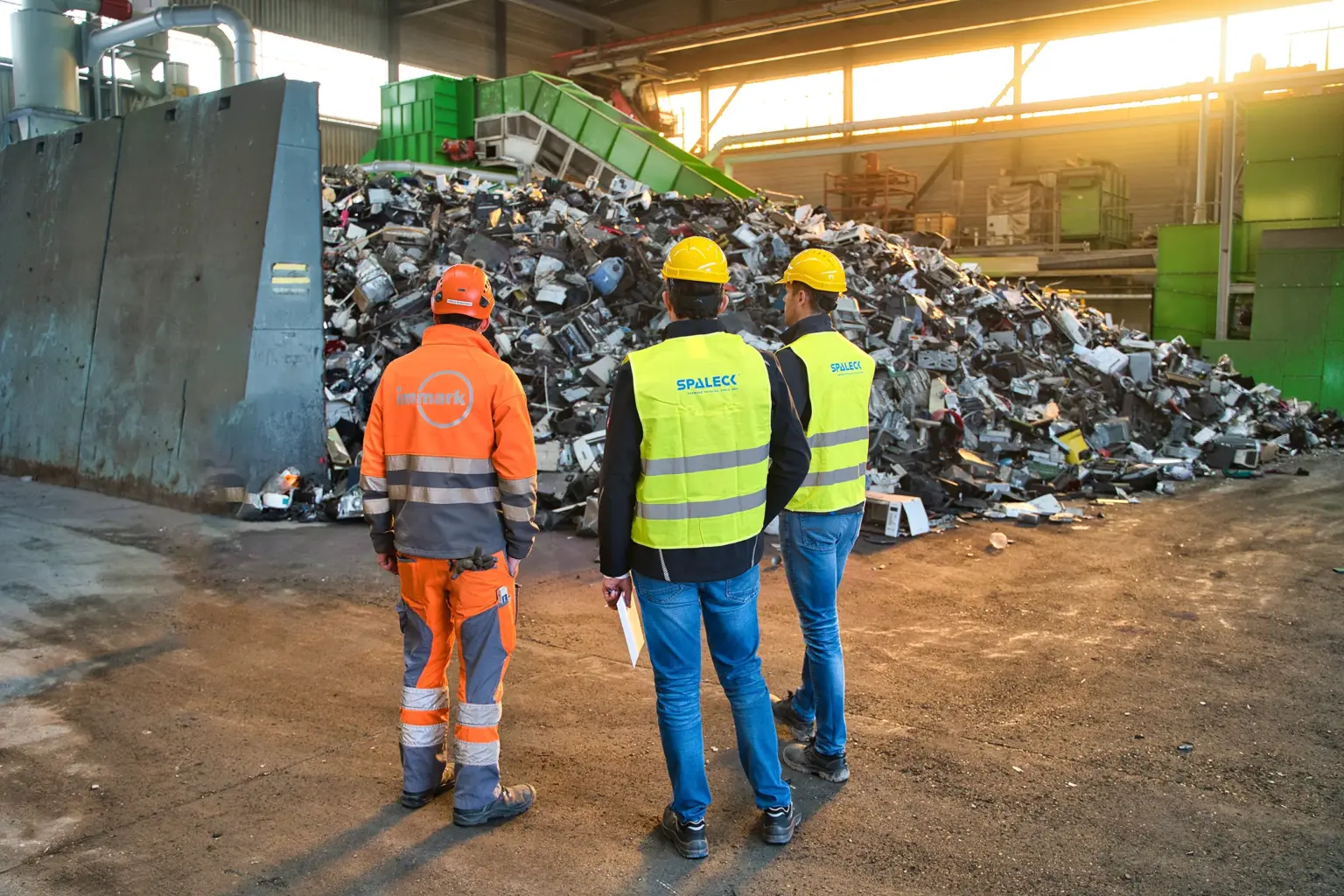 El jefe de proyecto de Immark y dos expertos en cribadoras de SPALECK se encuentran frente al material de entrada sin triturar destinado a la nueva planta de tratamiento de residuos electrónicos