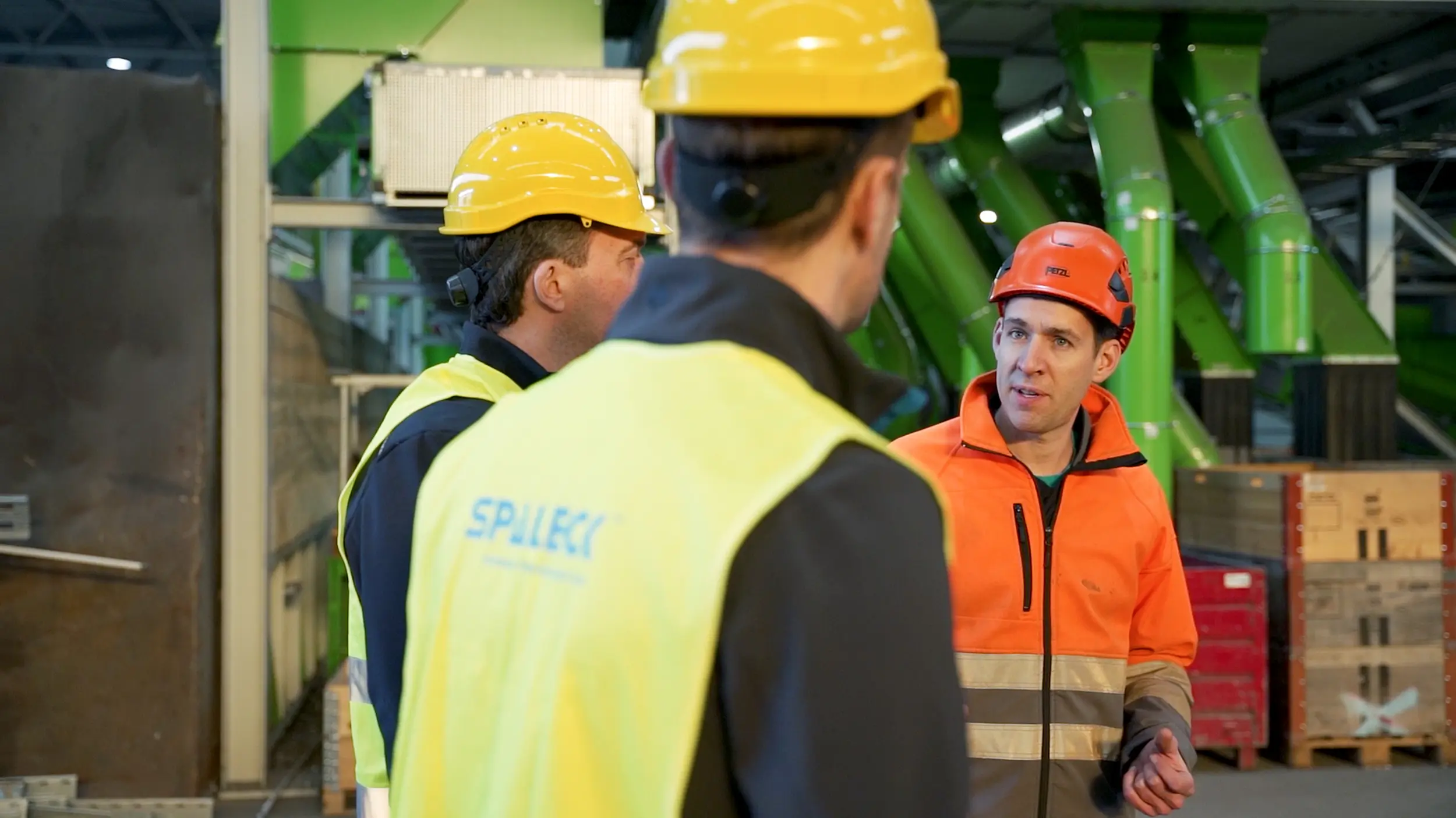 Unos trabajadores, equipados con ropa de protección, conversan en una planta de reciclaje.