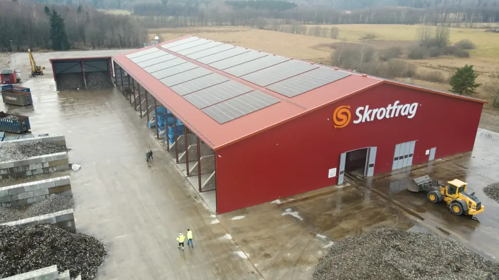 Planta de reciclaje de Skrotfrag para metales no ferrosos, con un edificio rojo y paneles solares.