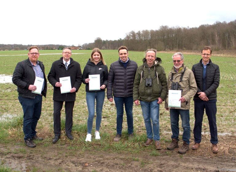 Un grupo de personas en un campo muestra documentos sobre la sostenibilidad en SPALECK.