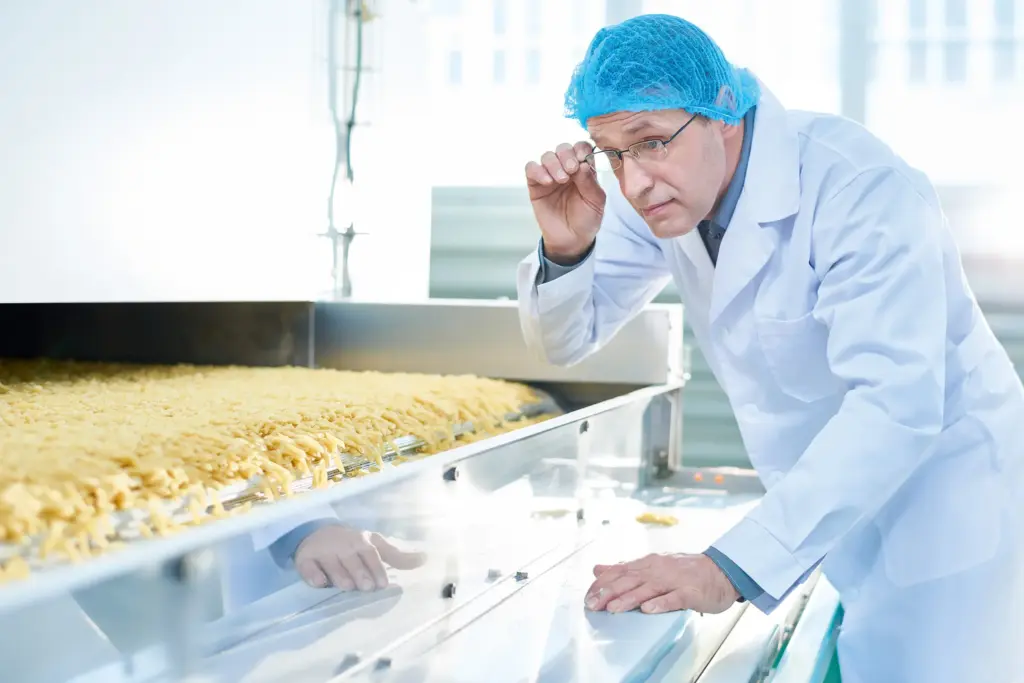 Un hombre con ropa de protección inspecciona la producción de alimentos.