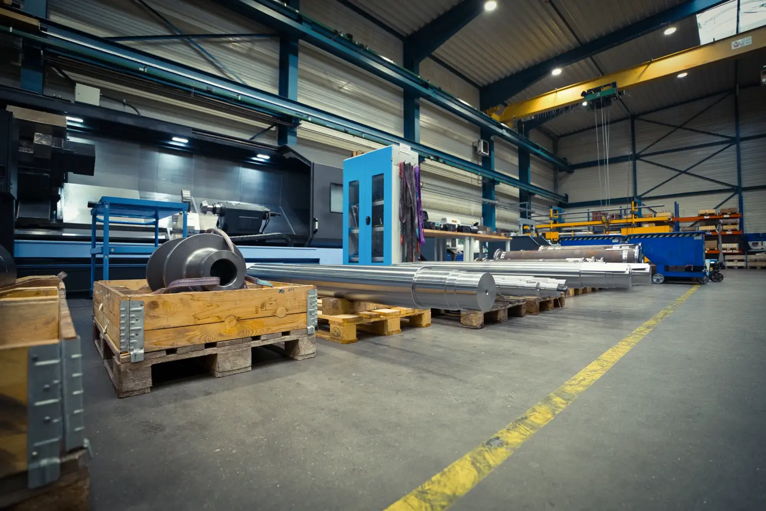 Nave industrial con piezas torneadas alargadas sobre palés.