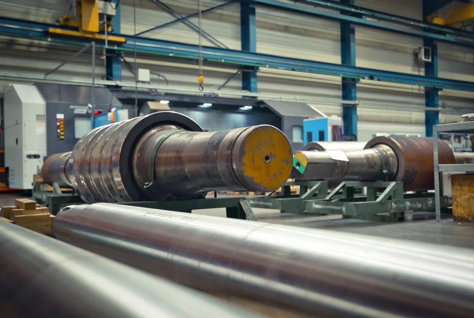 Grandes cilindros metálicos en una nave industrial, aptos para piezas torneadas largas.