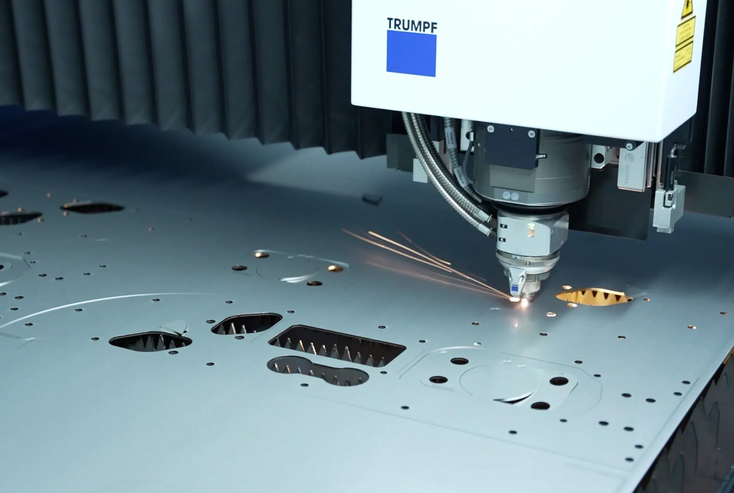 Fotografía detallada de un proceso de corte por láser en la fabricación de piezas cortadas con láser mediante una máquina de corte por láser