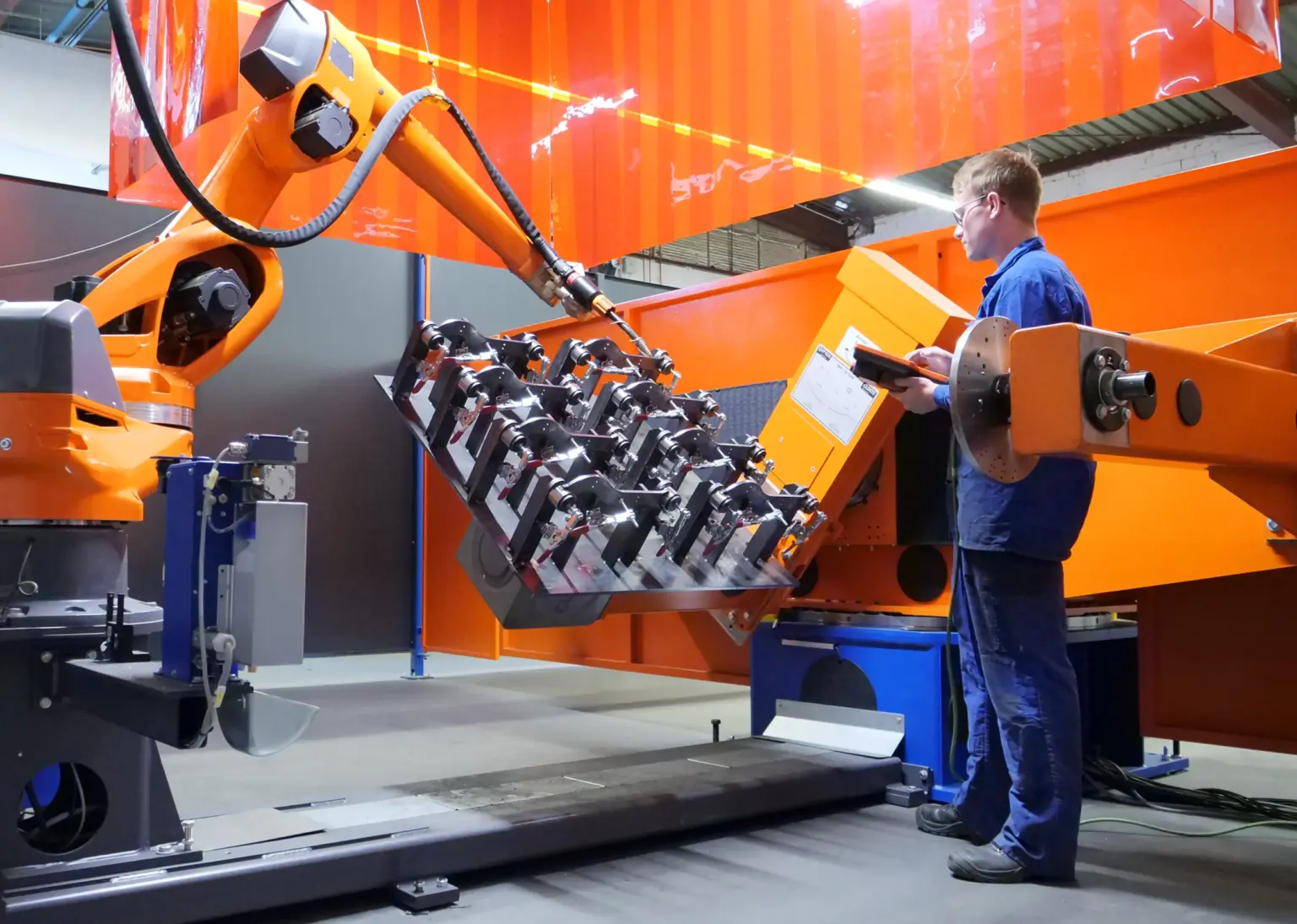 Un técnico en mecánica de construcción instruye y entrena a un robot de soldadura para que sepa cómo soldar una pieza en la empresa de subcontratación SPALECK