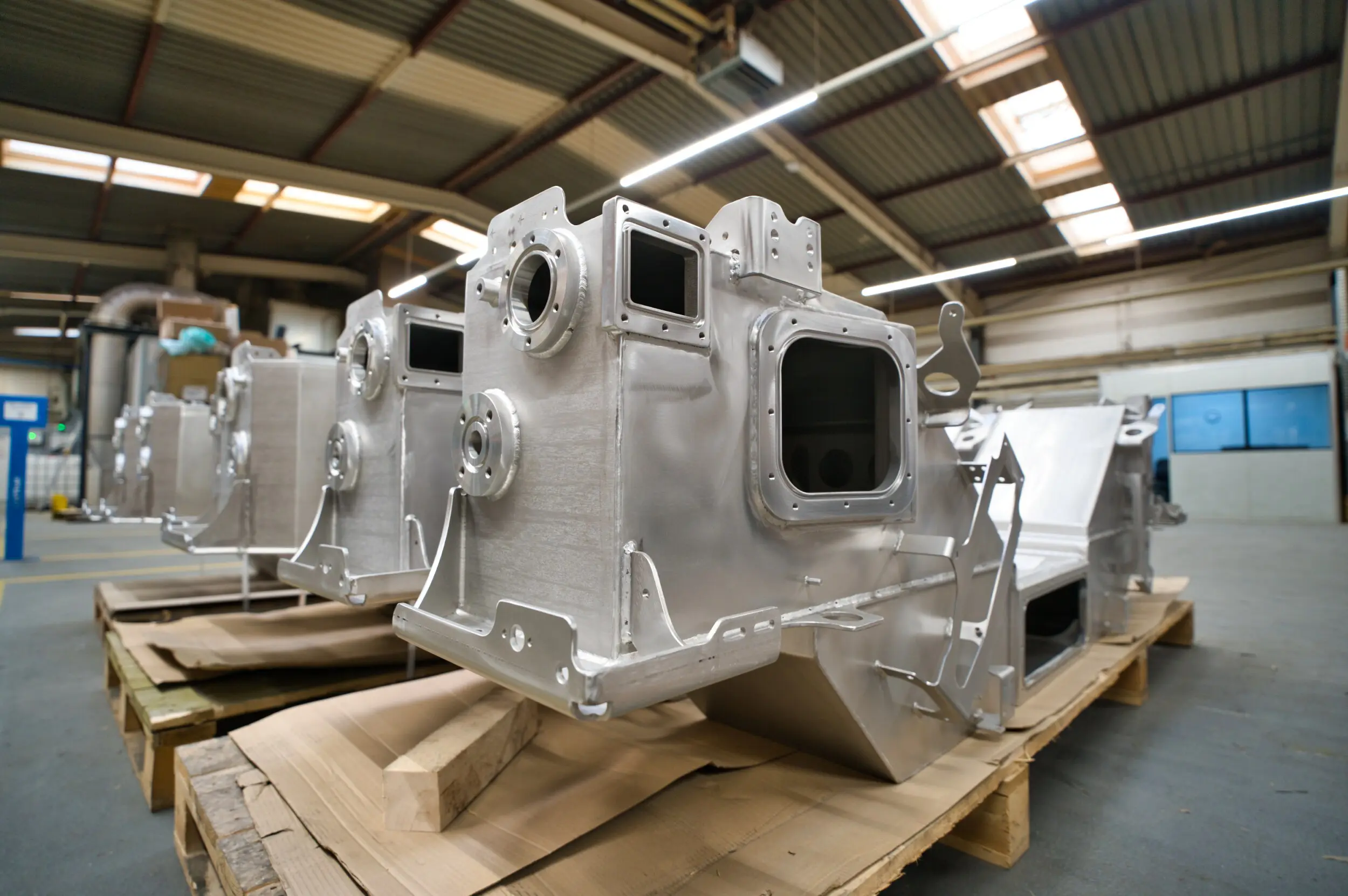 Grandes conjuntos metálicos en palés dentro de una nave industrial.