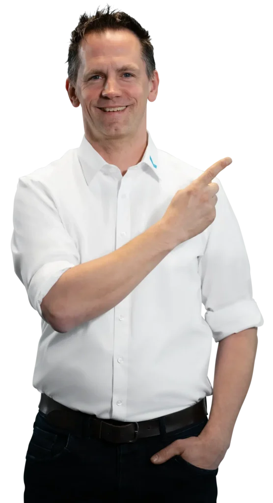 Un hombre con camisa blanca señala hacia un lado con una sonrisa.