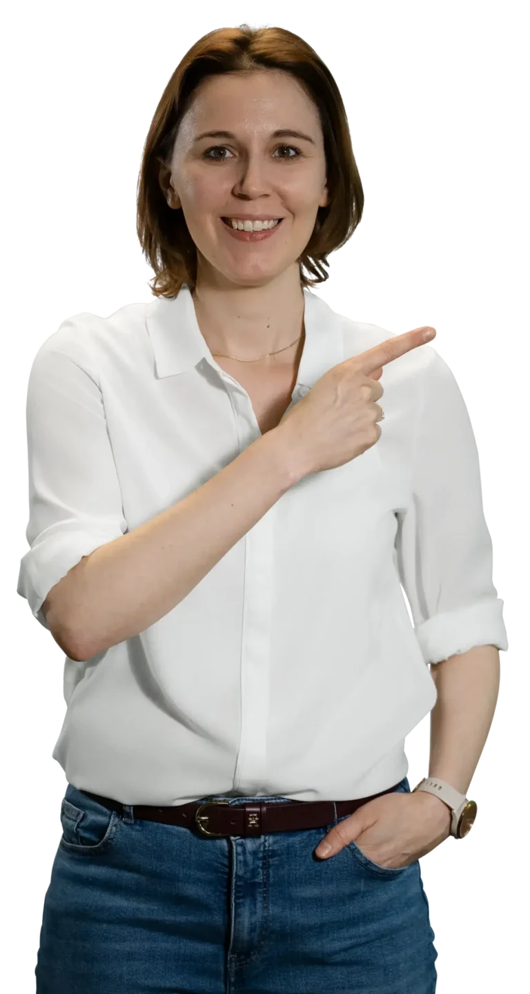 Una mujer con camisa blanca y vaqueros señala sonriendo hacia un lado.
