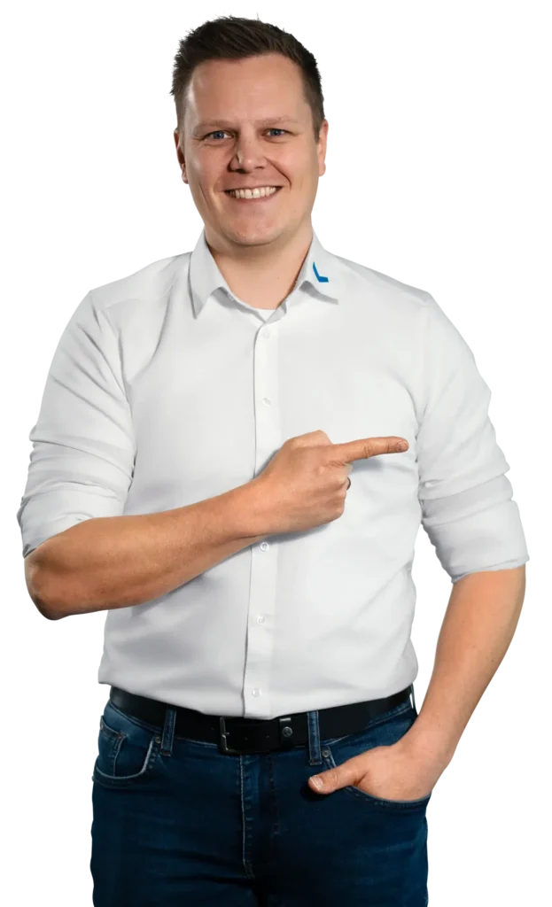 Un hombre con camisa blanca señala hacia un lado con una sonrisa.