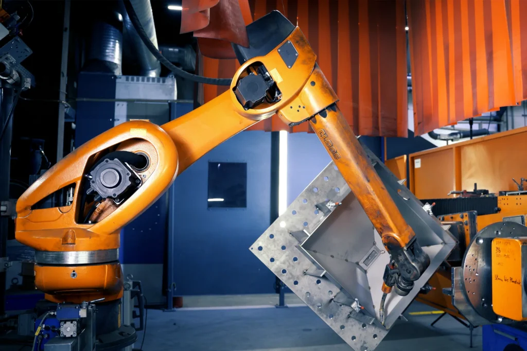 Un robot de soldadura se dispone a realizar la soldadura automatizada de un componente destinado a la industria ferroviaria. La fotografía se tomó en las instalaciones de SPALECK, empresa dedicada a la fabricación por encargo y al procesamiento de metales.