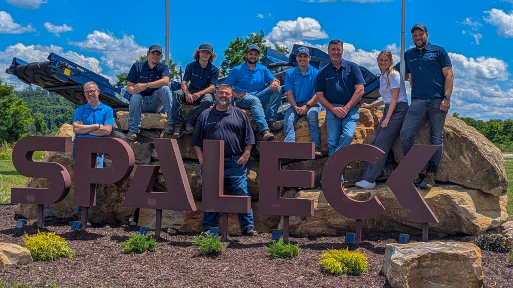 Foto de equipo de Spaleck USA junto al logotipo de Spaleck en Charleroi, con motivo de la inauguración de las instalaciones y bajo un cielo azul